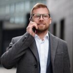 Professional man in a gray coat making a phone call outside in an urban setting.